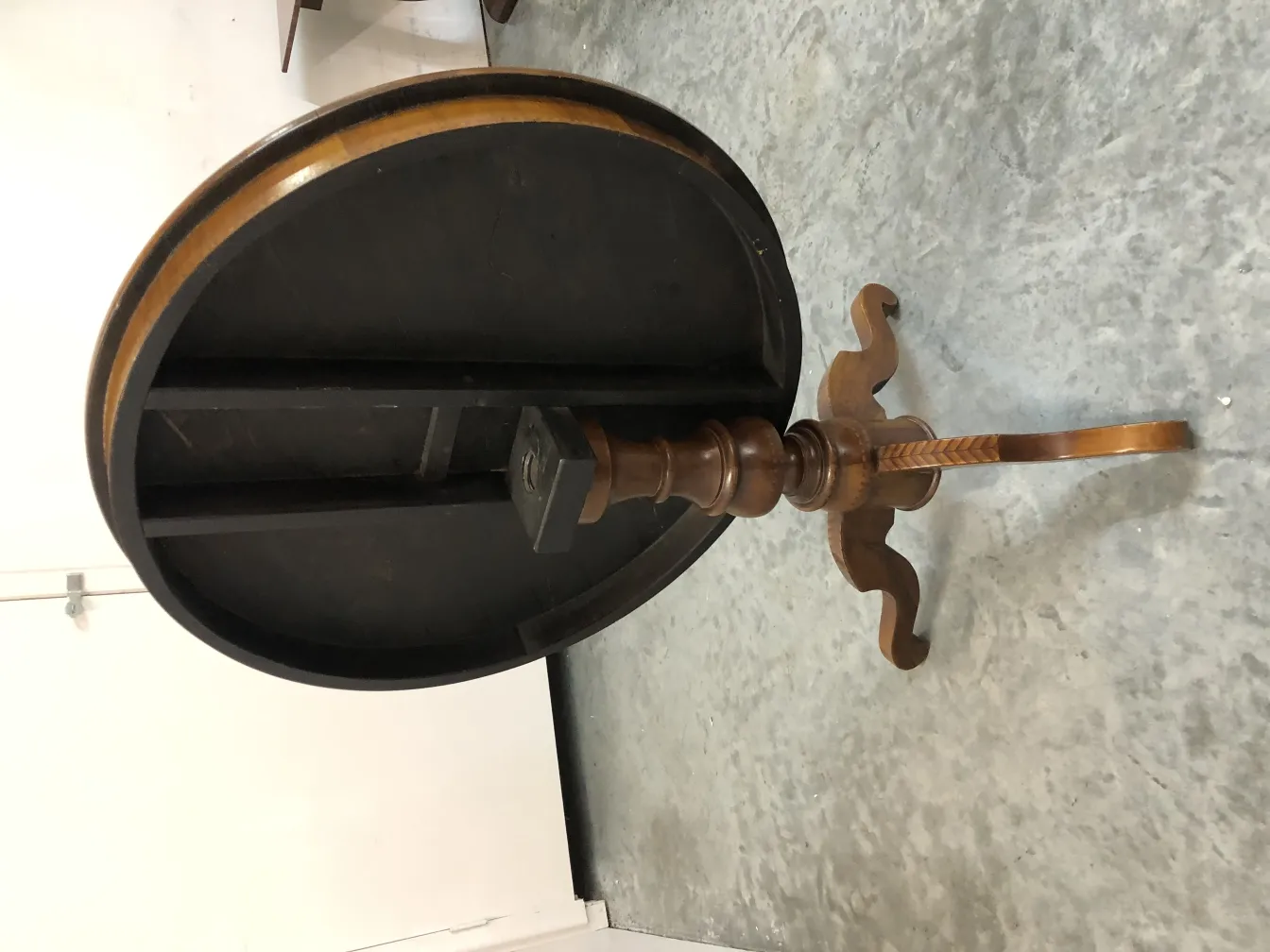 Antiker runder Tisch mit dekorativem Design und kunstvollen Beinen, in einem neutralen Umfeld platziert.