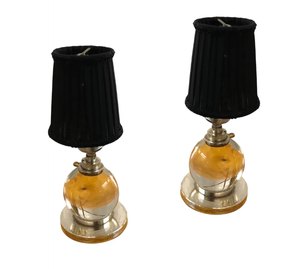 2 lâmpadas de mesa antigas com detalhes distintos e sombra preta, ambientadas em um ambiente clássico.