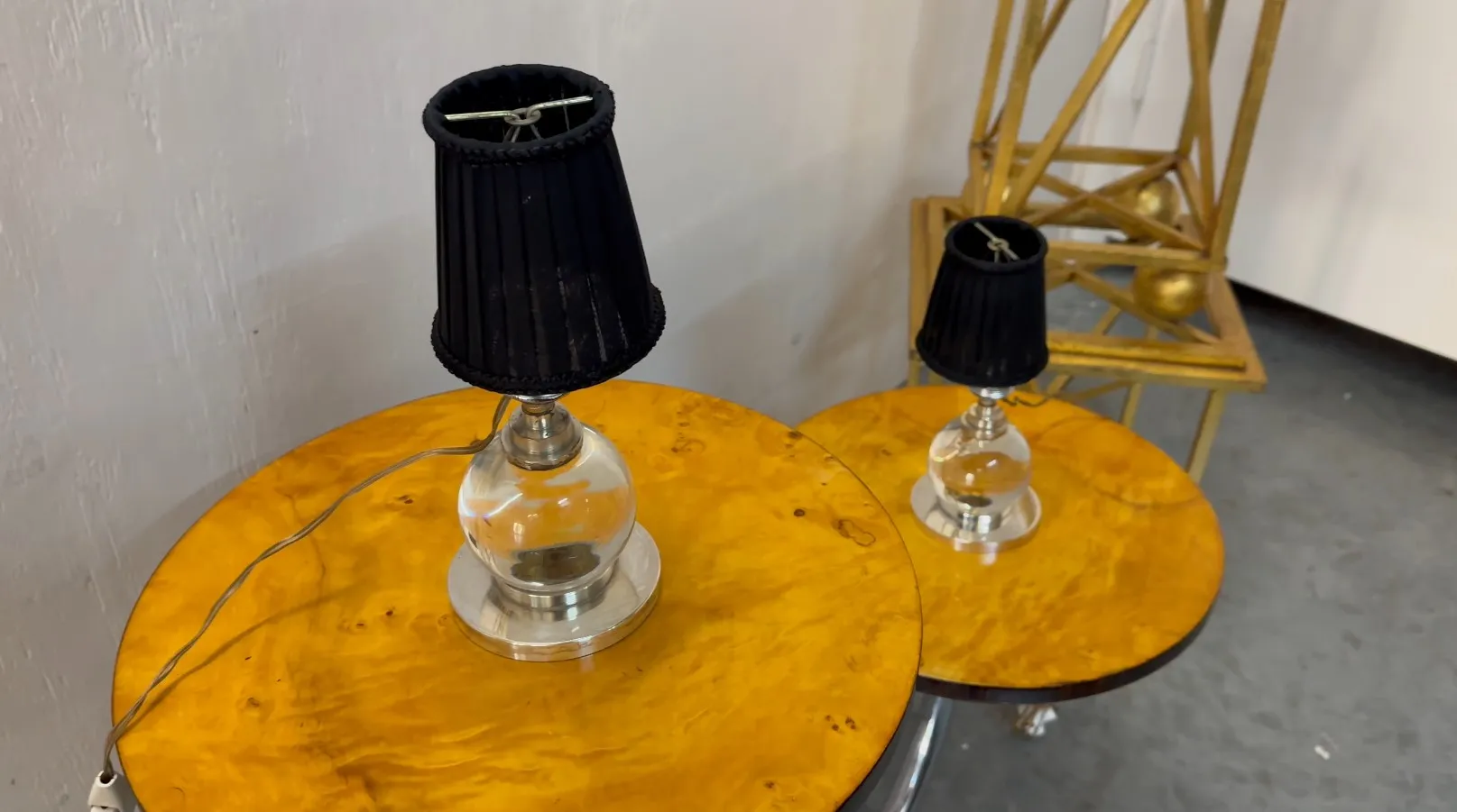 duas lâmpadas de mesa antigas com sombreiros pretos e bases metálicas, decoradas em um ambiente elegante