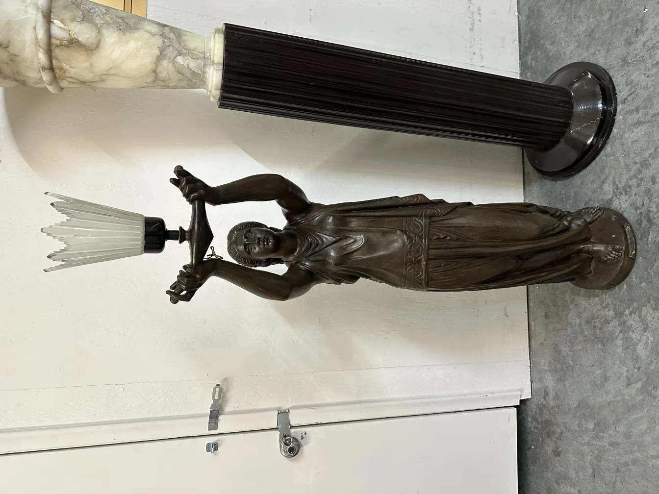 escultura antiga representando uma figura masculina segurando um objeto decorativo em forma de coroas