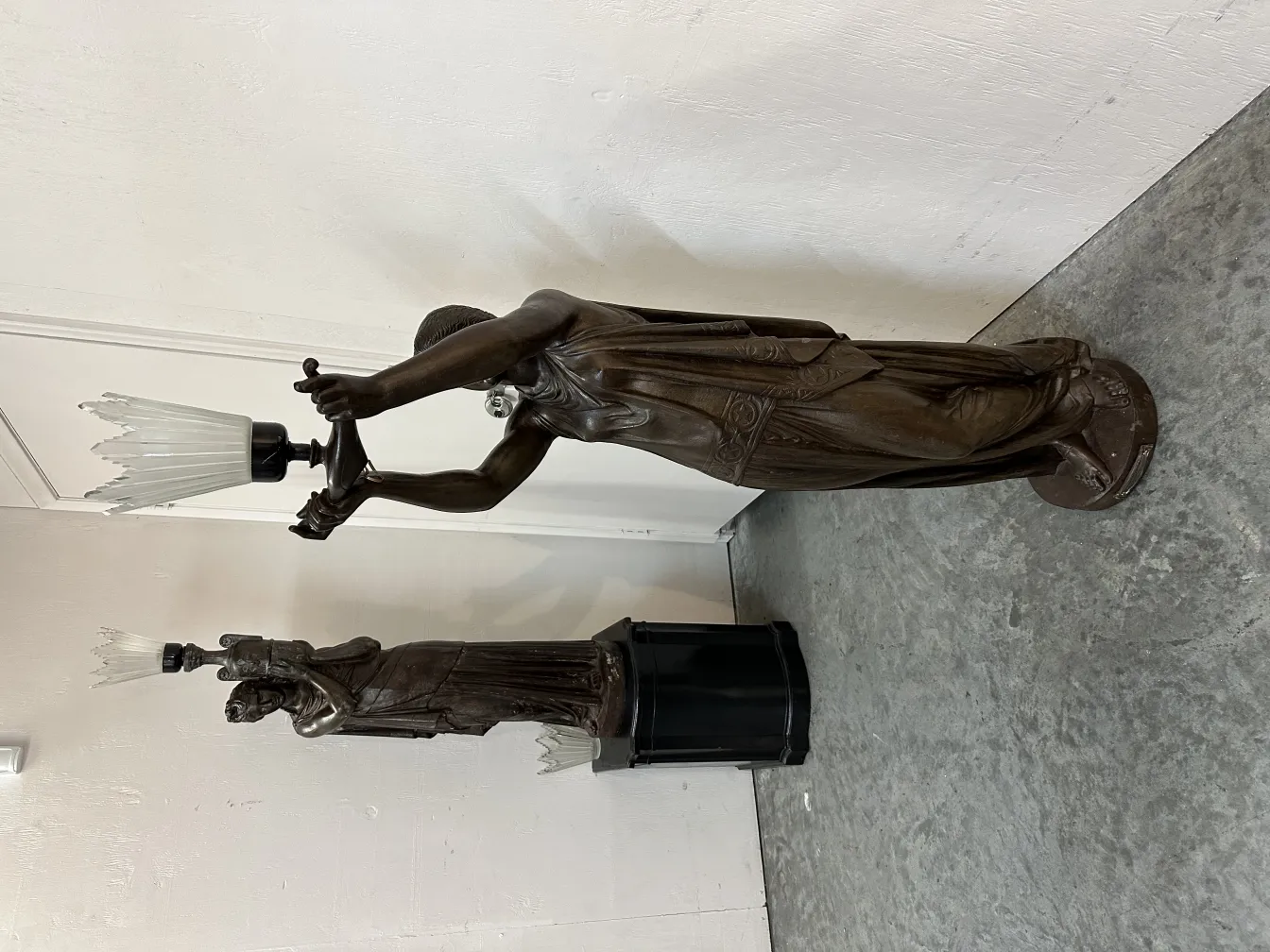 antike Skulptur mit einer menschlichen Figur, die eine Lampe hält