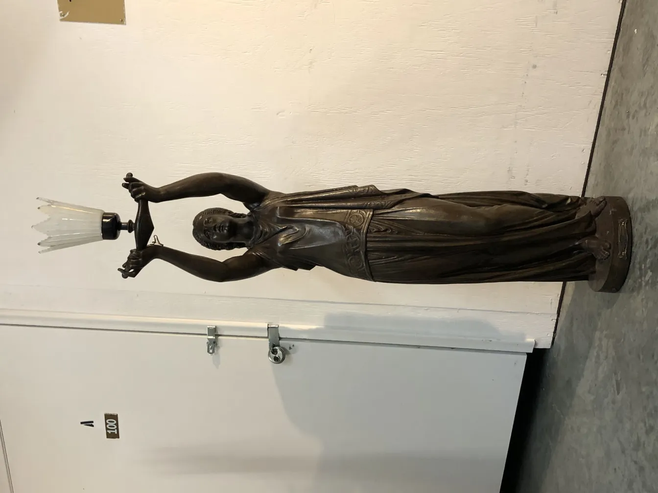 Antike Val-Dosne-Skulptur mit Licht, schlanke Figur in einfacher Umgebung.