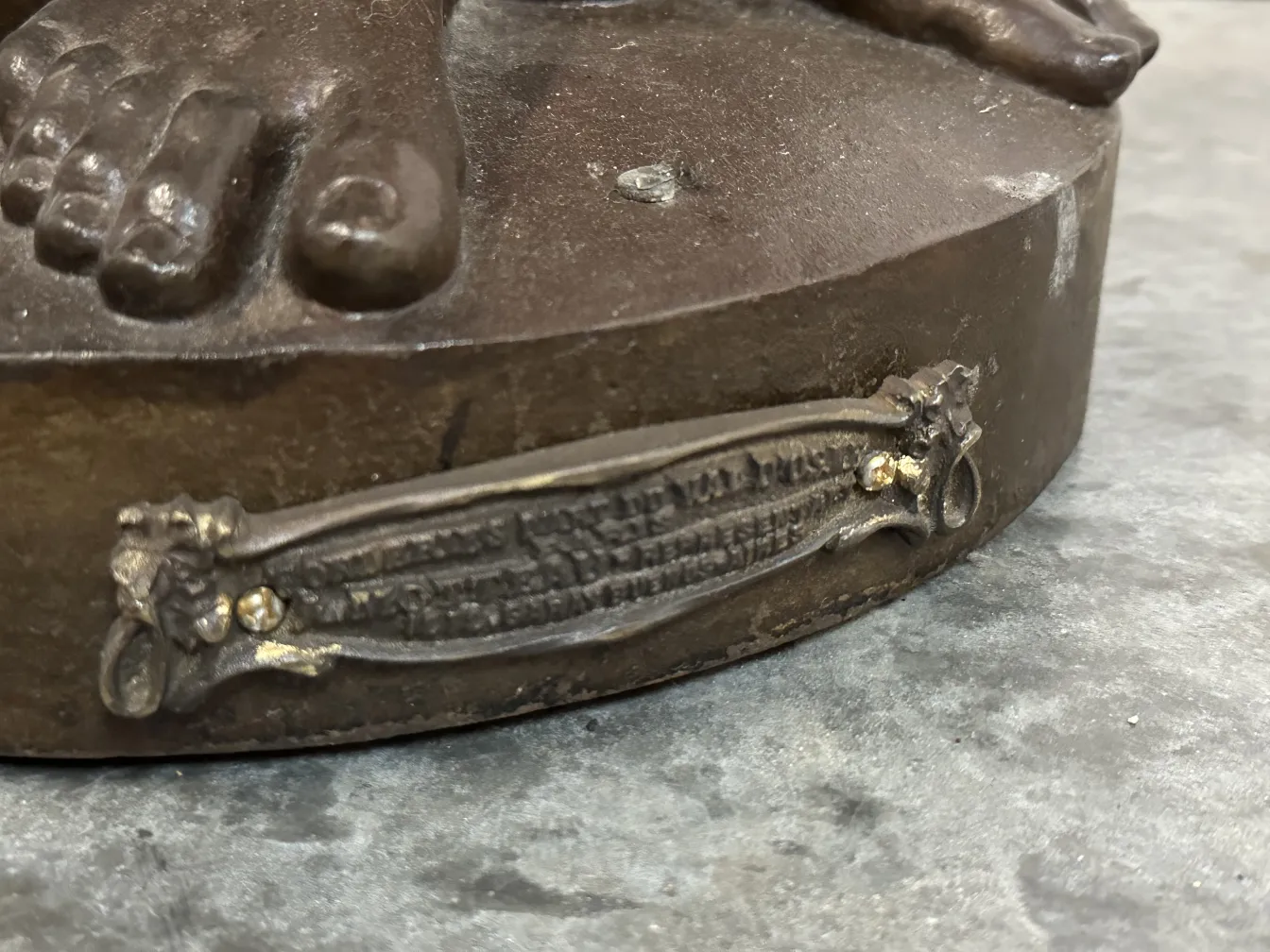 Detail of antique sculpture Val D'Osne, featuring feet and ornate base.