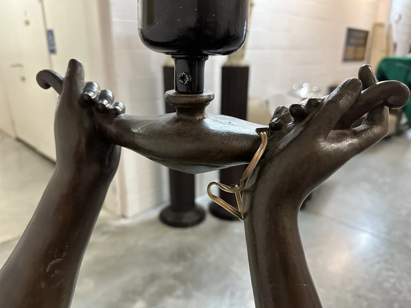 escultura que representa manos sosteniendo una lámpara antigua, ambiente y detalles visuales suaves