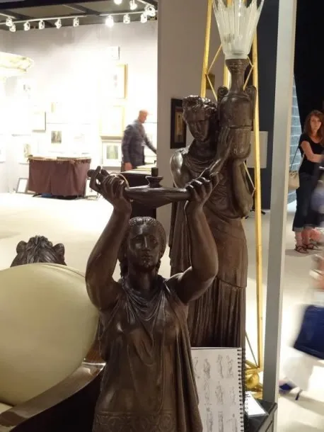 escultura antigua en un ambiente de galería, figura femenina con lámpara