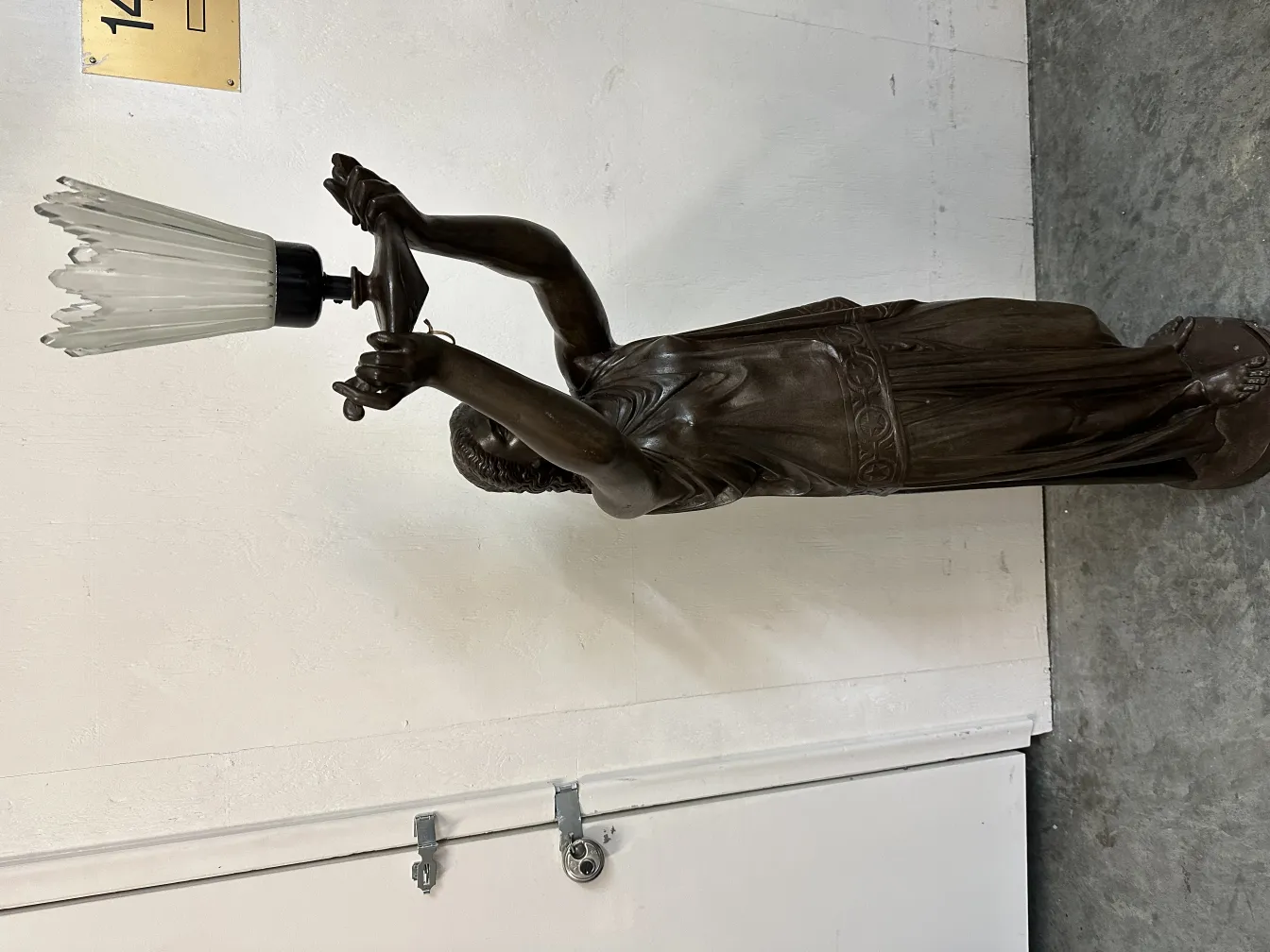 Scultura antica di figura femminile che regge una lampada.