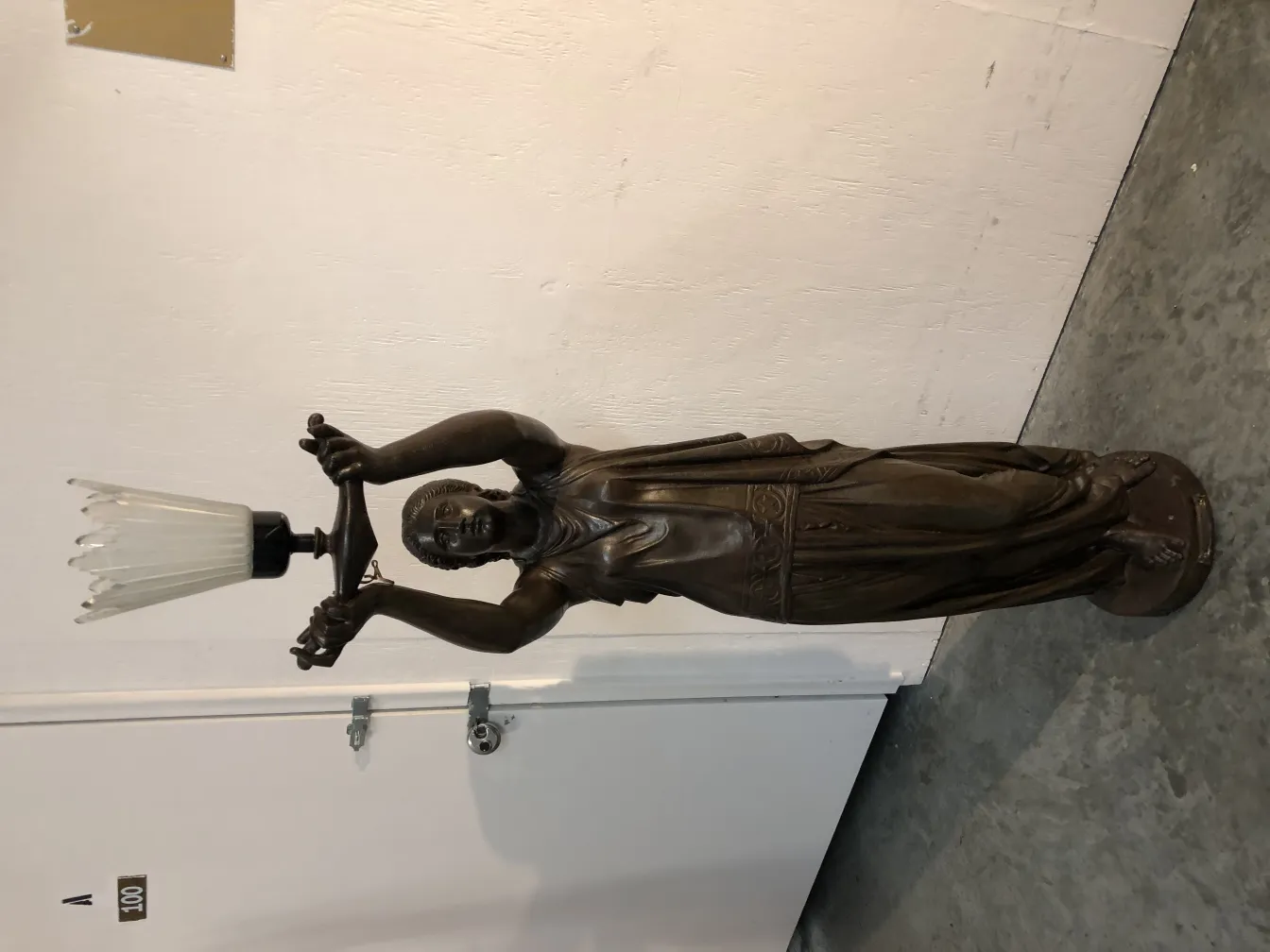 Antique sculpture Val D´Osne depicting figure holding light in a simple setting