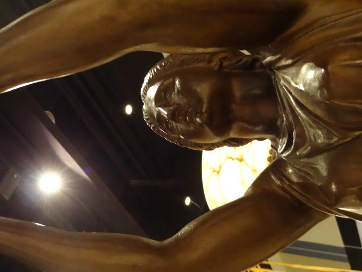 antique sculpture of a female figure with raised arms