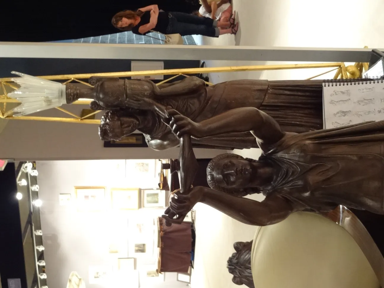 Escultura antiga com detalhes finos, figuras relevantes ao fundo.