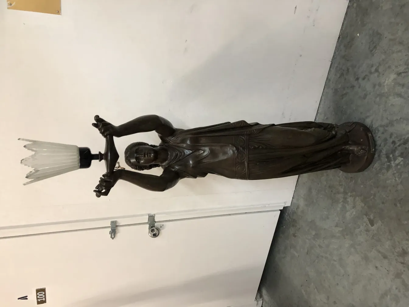 scultura antica di Val D´Osne che tiene una lampada con luce diffusa, dettagli su viso e abbigliamento.