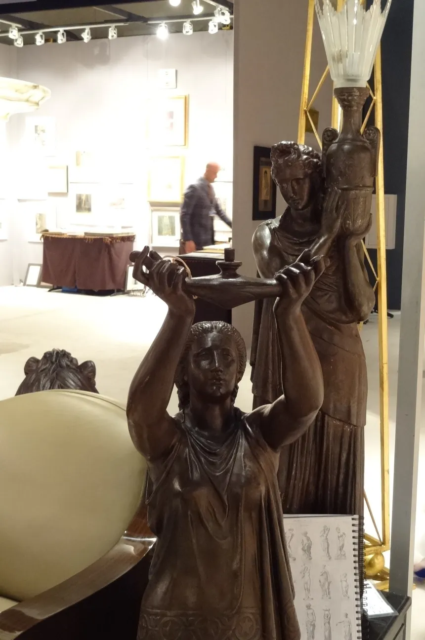 scultura antica di donna che tiene una lampada con sfondo di galleria