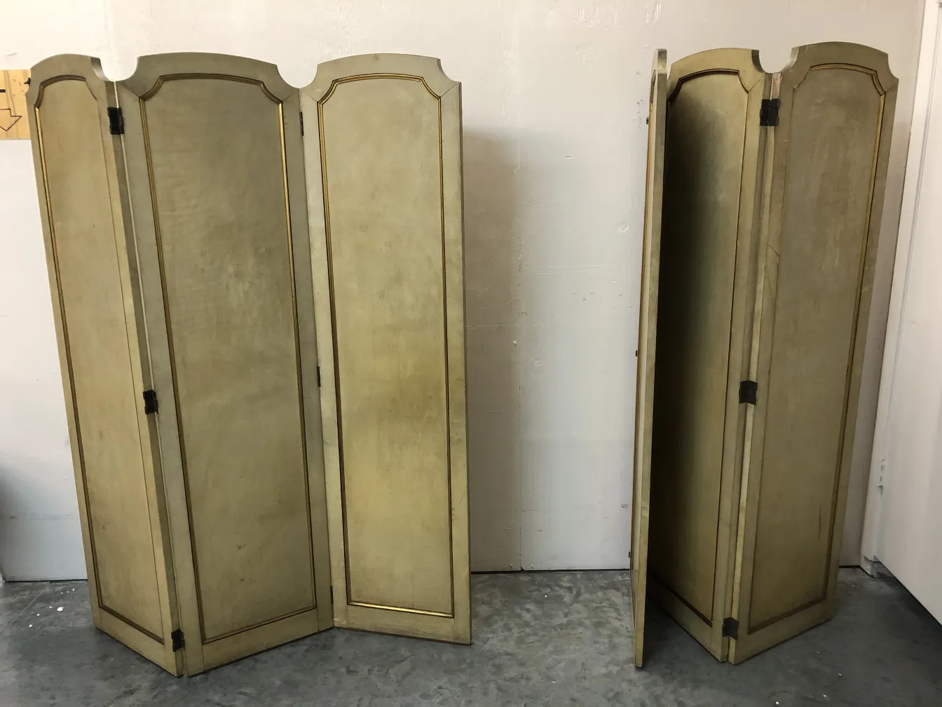 two antique folding screens with decorative gold details, one upright and one partially folded
