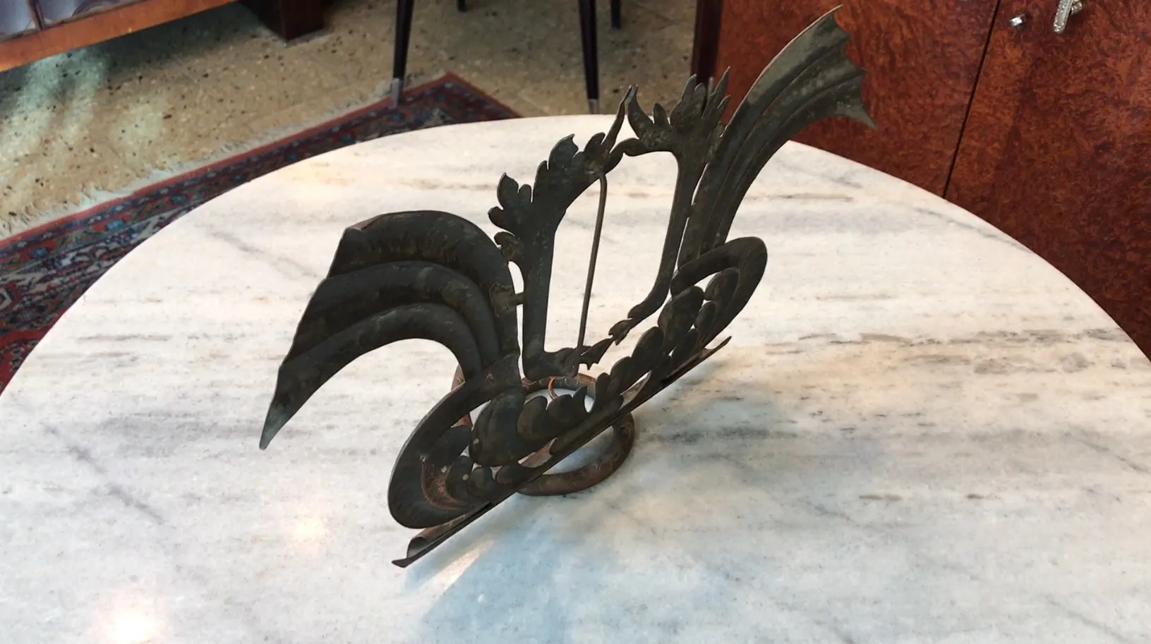 Portarretrato antiguo con diseño ornamental y detalles artísticos, colocado sobre mesa. Fondo de ambiente cálido.