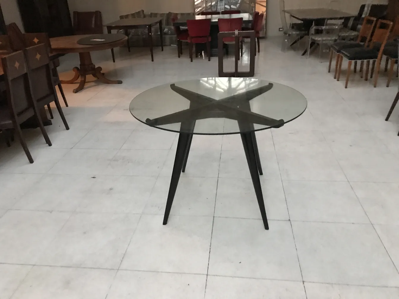 Mesa de comedor antigua redonda con patas negras, ambiente clásico.