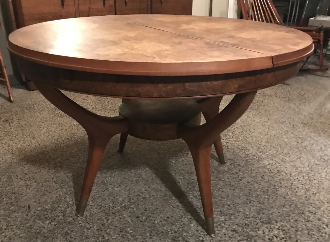 Mesa antiga de jantar, formato oval, pernas elegantes, ambiente aconchegante.