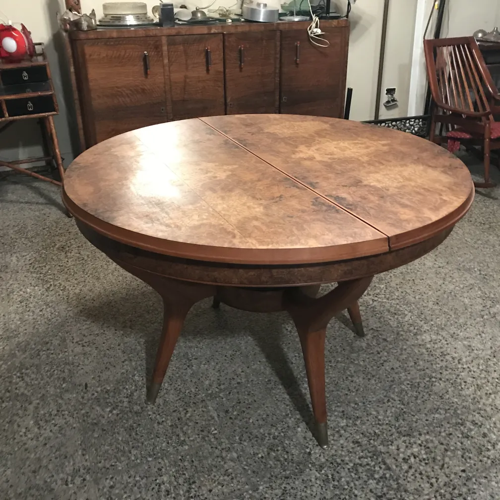 Tavolo da pranzo antico, con superficie rotonda e gambe eleganti. Ambientazione accogliente con oggetti decorativi.