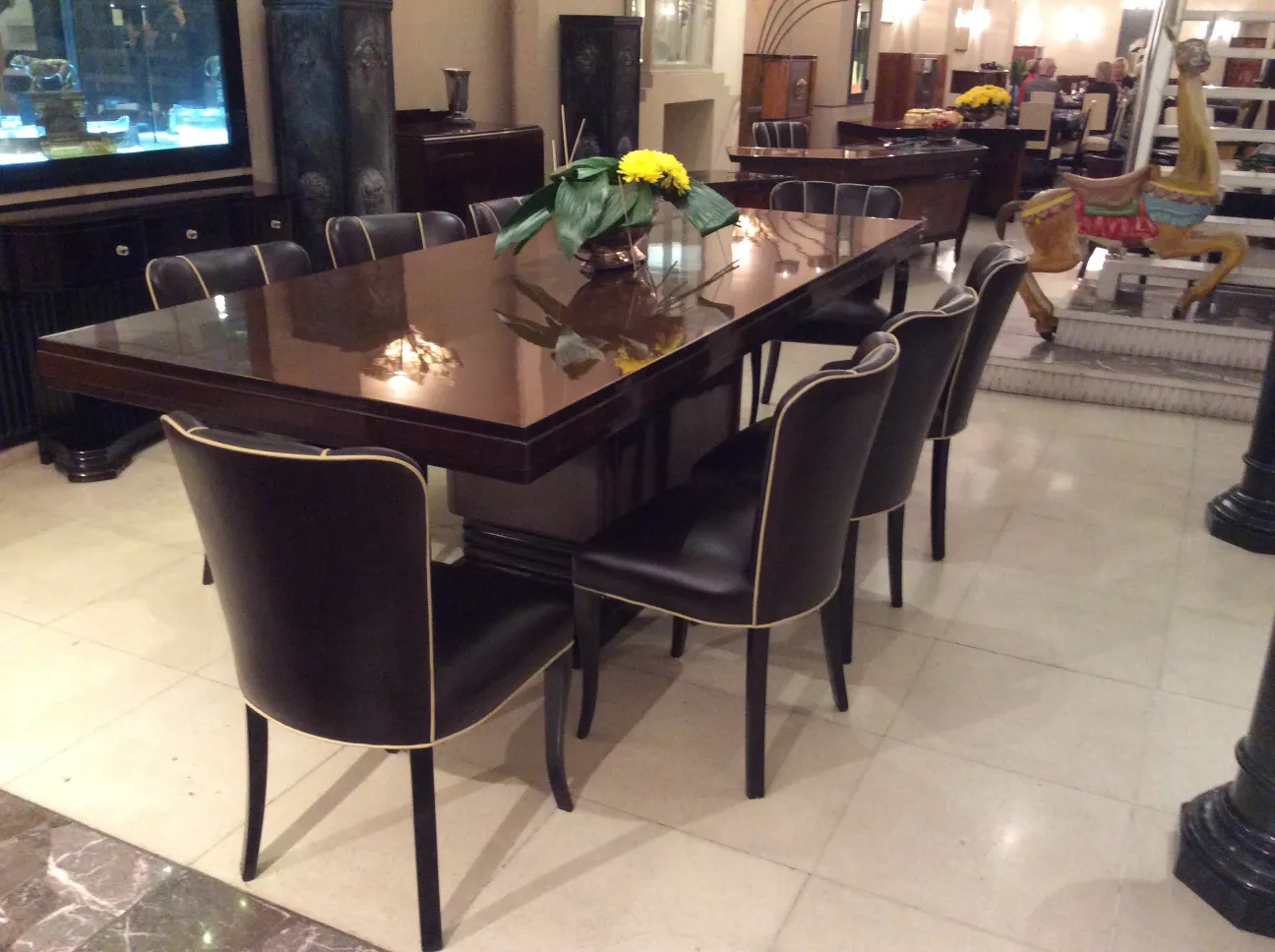 Antique dining table with eight chairs, decorated with flowers. Elegant setting.