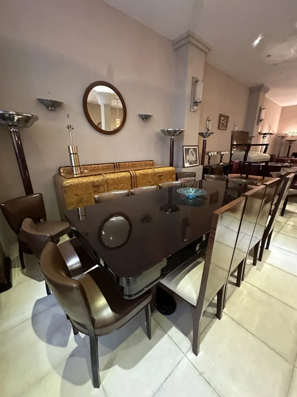 Mesa de jantar antiga para 10 pessoas em um ambiente elegante, com cadeiras e luzes decorativas.