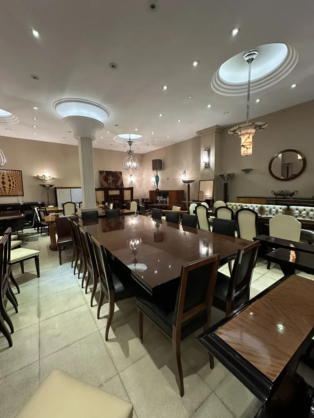 Grande table à manger antique pour dix personnes, entourée de chaises élégantes dans un cadre chaleureux.