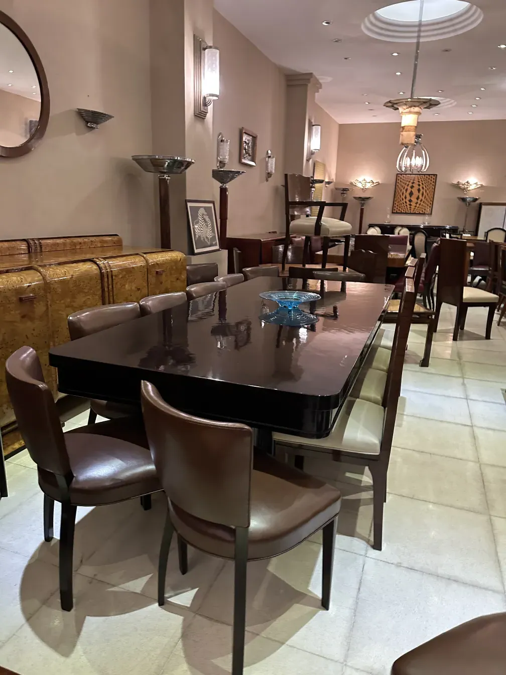 Mesa de jantar antiga para 10 pessoas, cercada por cadeiras em um ambiente elegante.