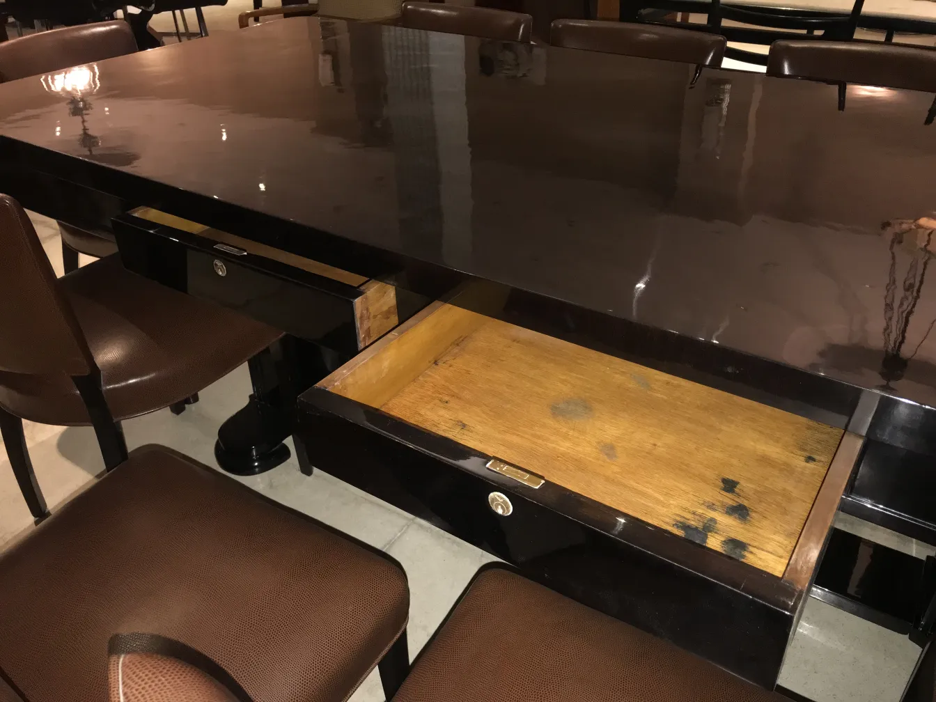 Table à manger antique pour 10 personnes avec tiroirs visibles et chaises en cuir marron dans un cadre élégant.