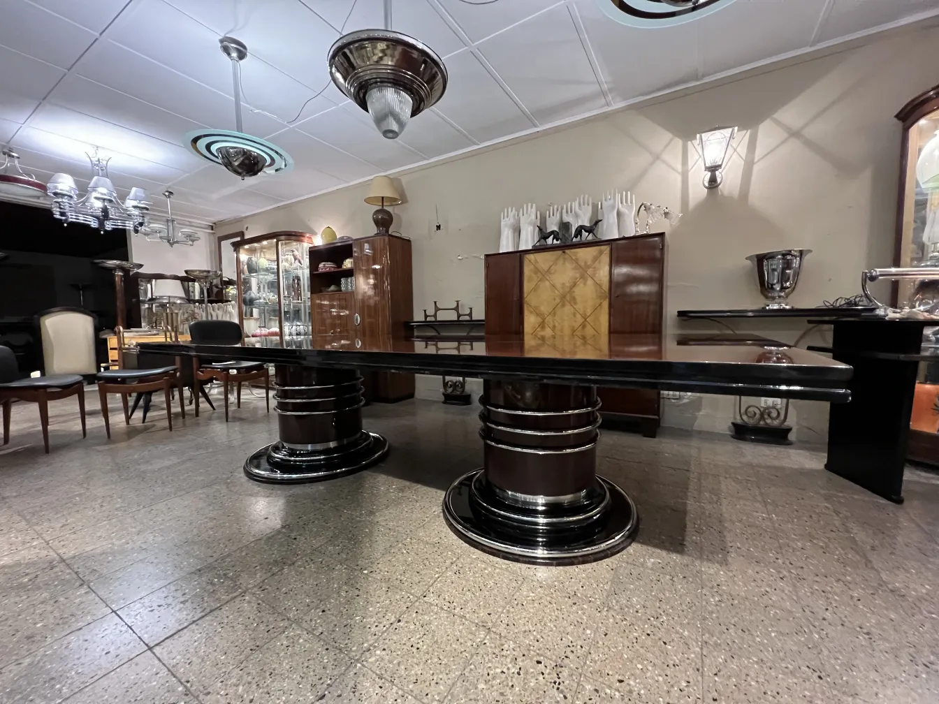 Antique dining table for 14 people in an elegant setting with hanging lamps.