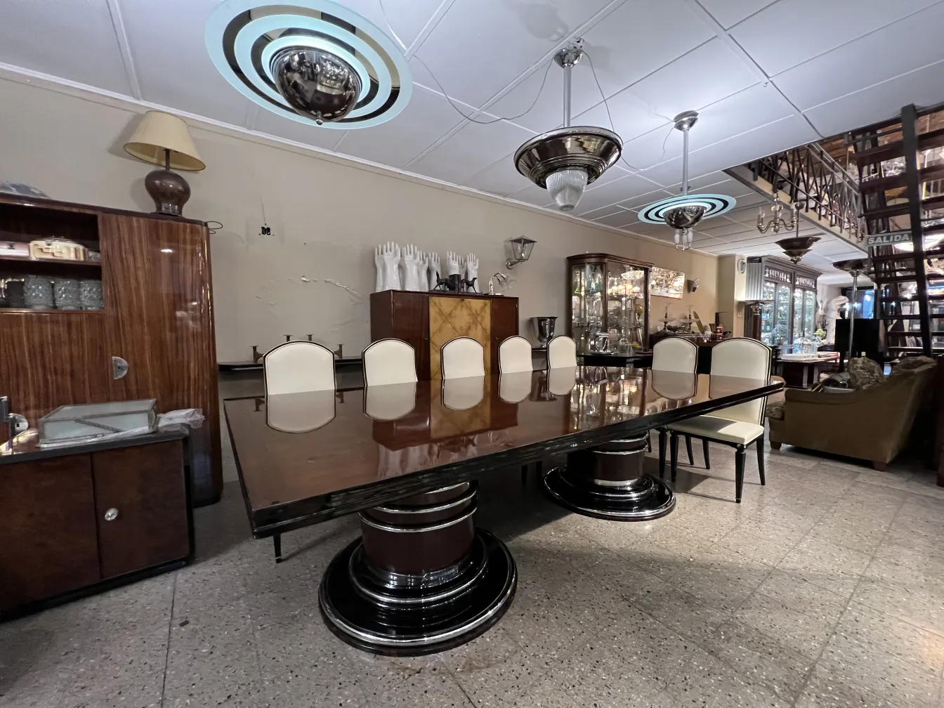 Mesa de jantar antiga para 14 pessoas com cadeiras brancas em um ambiente elegante.