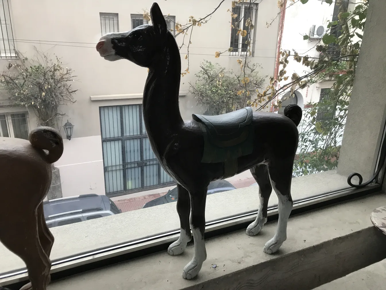 Figurine de lama décorative antique se tenant devant une fenêtre.