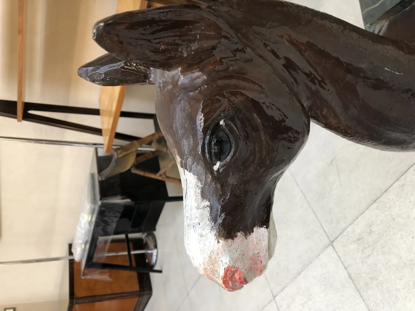 testa di antica lama in ceramica con dettagli decorativi. Sfondo di vari mobili.