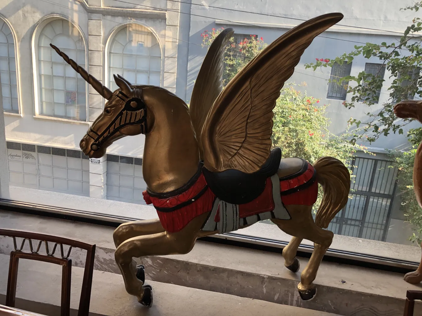 Unicorno antico dorato con ali davanti alla finestra