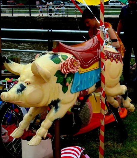 Antigua escultura decorativa de un chancho con flores, colorido y vibrante.