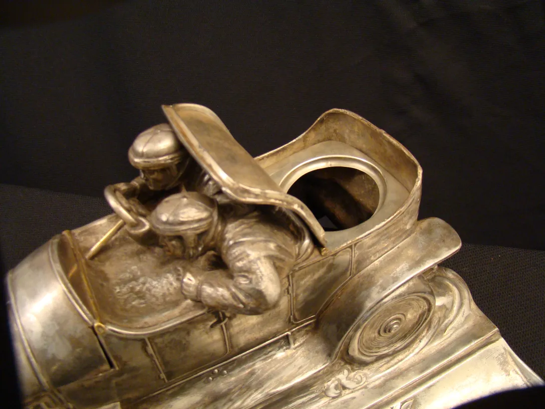 Antique inkwell in the shape of a car with two drivers