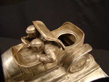 Tintero antiguo con forma de coche de carrera, detalle ornamental.