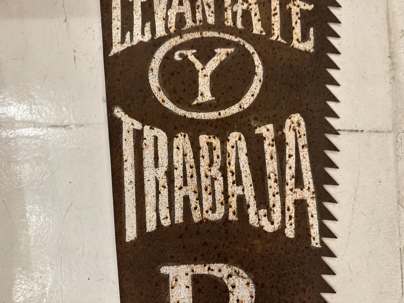 Antique advertising hand saw with visible inscriptions on rusty background