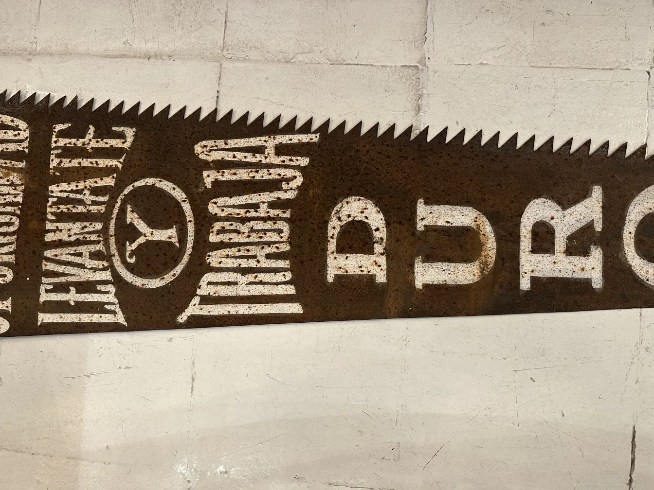 Antike Handsäge mit weißen Inschriften auf rostigem Hintergrund