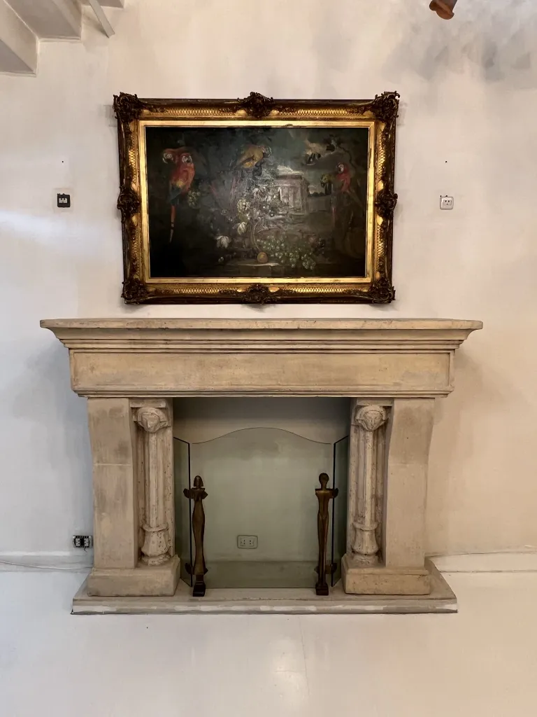 vintage fireplace front with intricate design and painting above