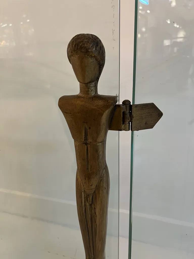 escultura antiga reminiscente de alberto giacometti na frente da lareira, com detalhes simples e um ambiente aconchegante.