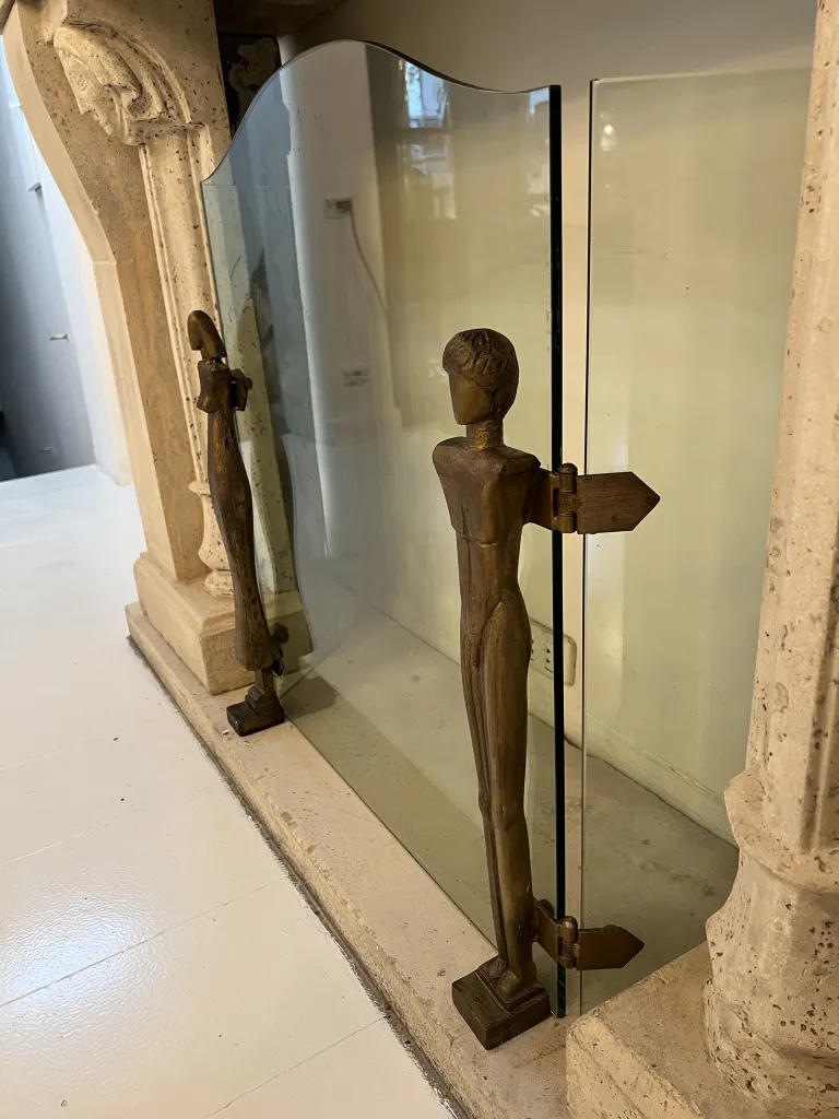 Frente de lareira antigo com esculturas de Alberto Giacometti, figuras estilizadas em cada lado.