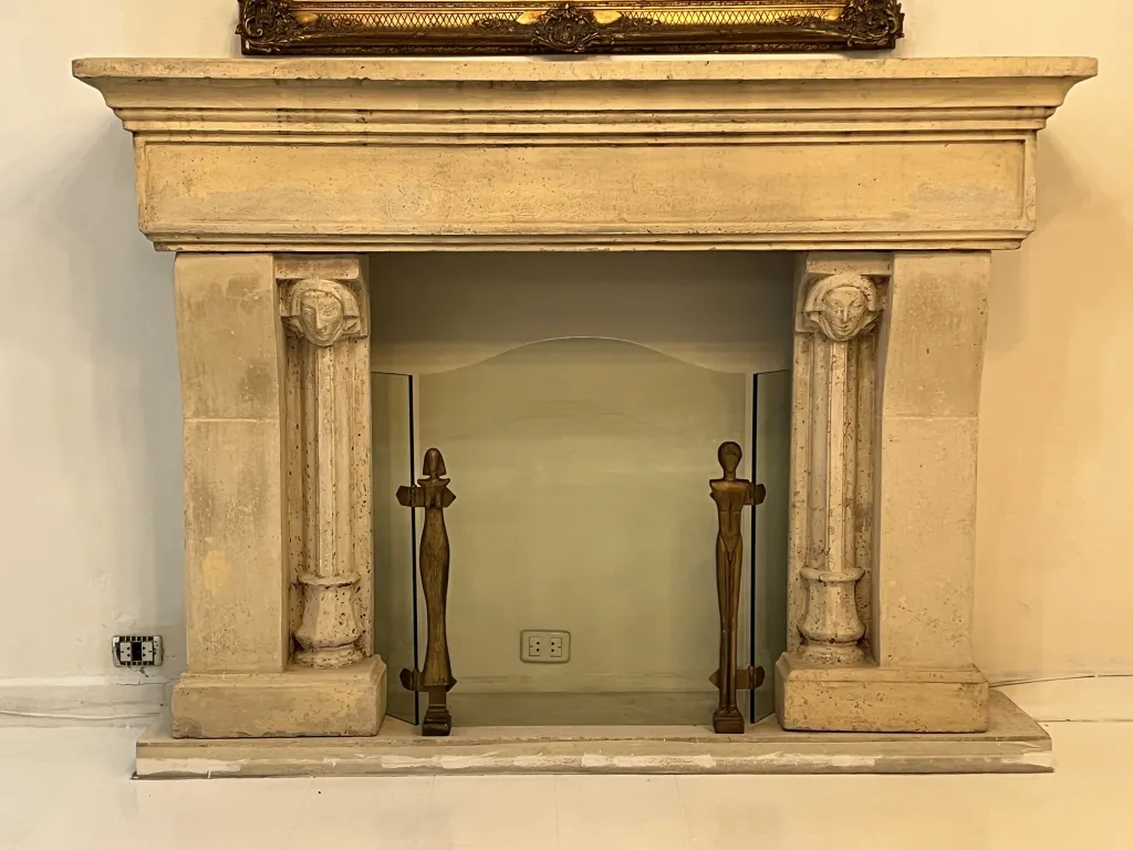 Frente de lareira antiga com detalhes e decoração, inclui figuras de Alberto Giacometti, ambiente aconchegante.