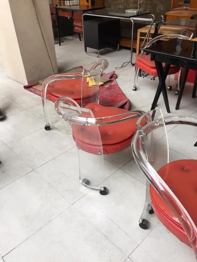 Cuatro sillones antiguos con cojines rojos en un entorno moderno.