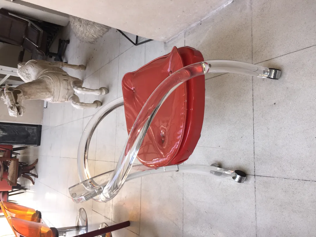 Quattro poltrone antiche rosse e trasparenti, decorando un ambiente elegante.