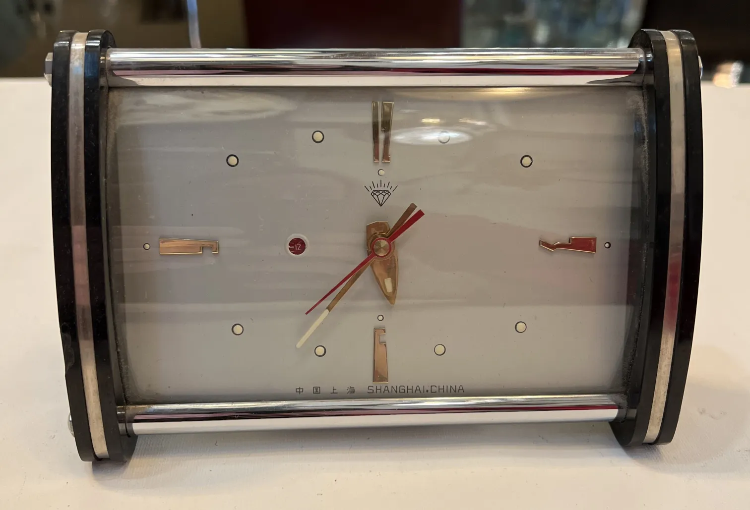 Reloj antiguo de mesa con manecillas doradas y rojo.