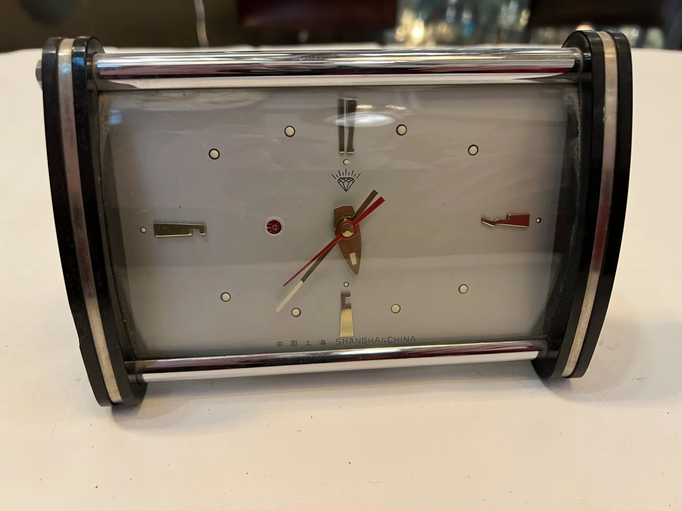 reloj antiguo de mesa con agujas doradas y fondo blanco
