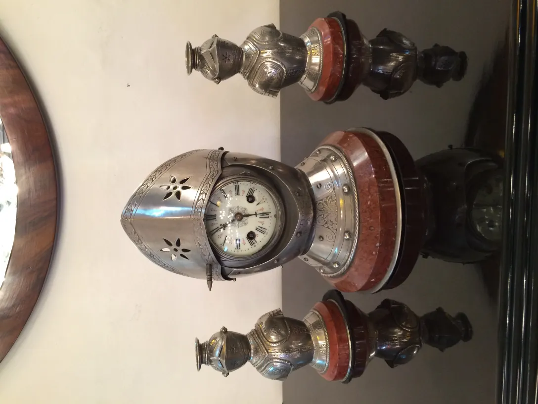 Reloj antiguo con candelabros decorativos en la mesa.