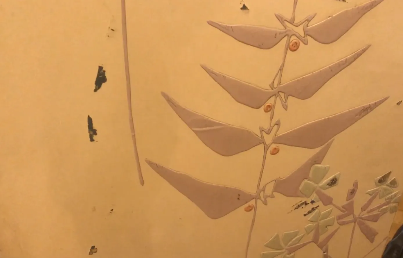 Antiker Paravent mit zartem Blatt- und Blütenmuster auf sanftem Hintergrund.