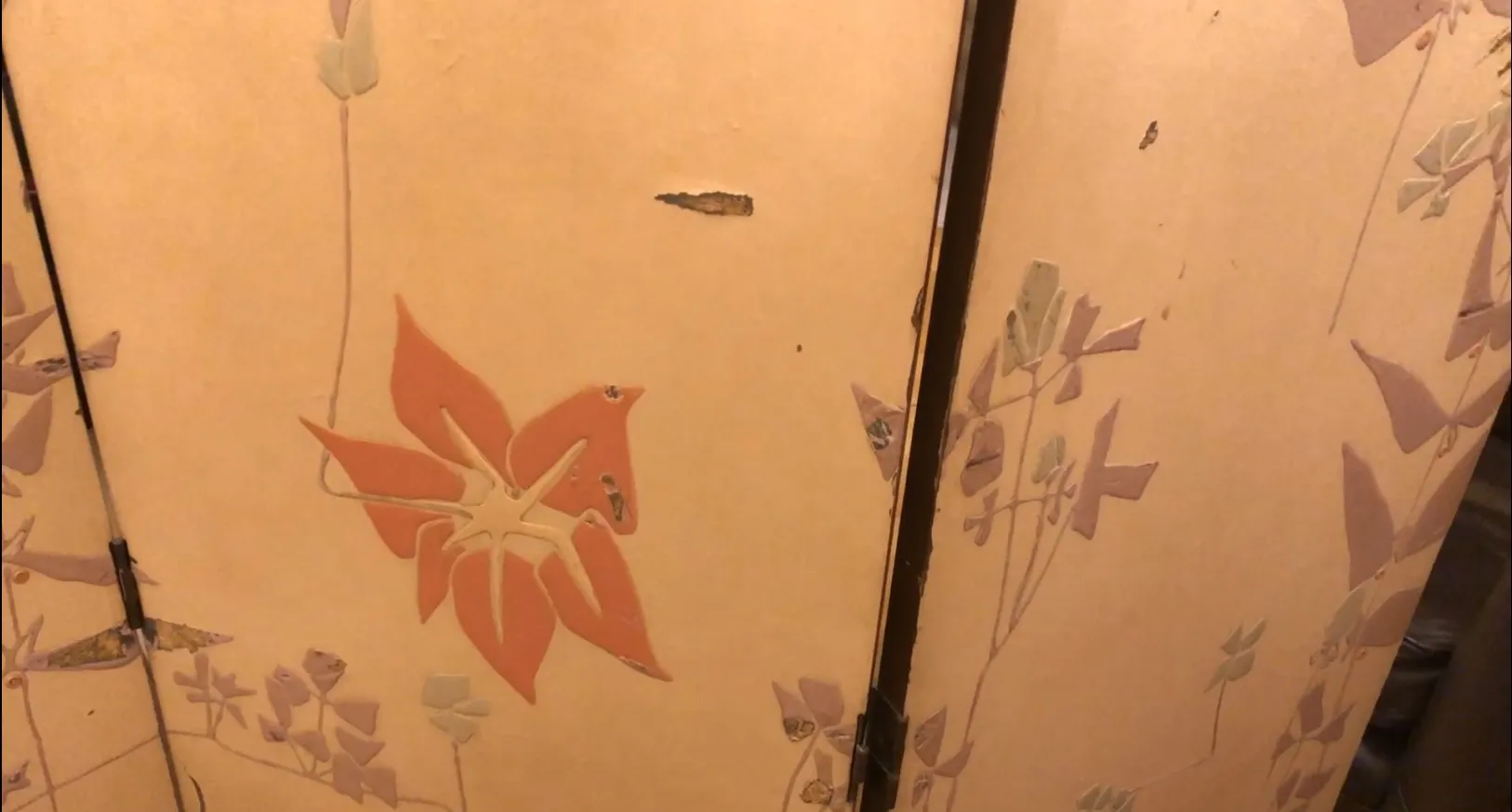 Paravent ancien avec motifs floraux dans des couleurs douces.