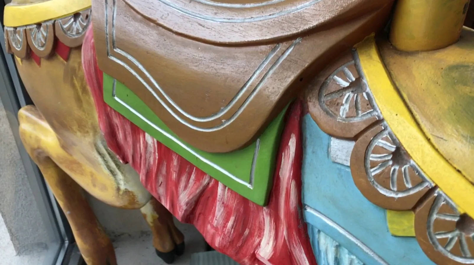Antique colorful carved llama with decorative features.