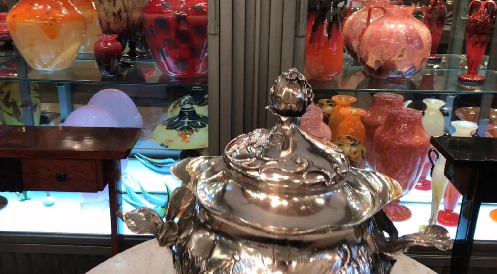 装饰性的WMF潘趣酒碗，背景中有复杂的图案和色彩斑斓的花瓶。