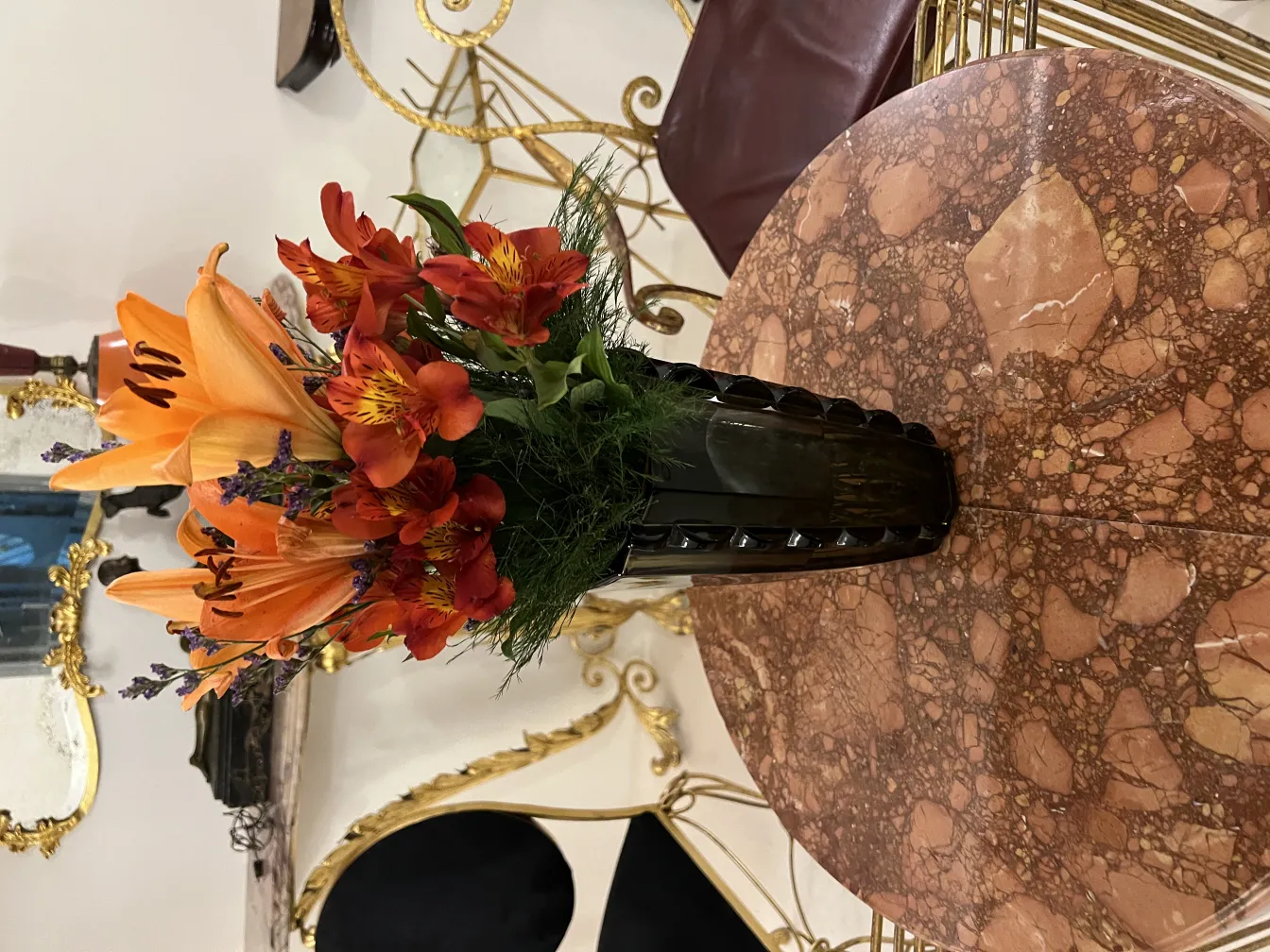 Florero antiguo con flores coloridas en una mesa elegante