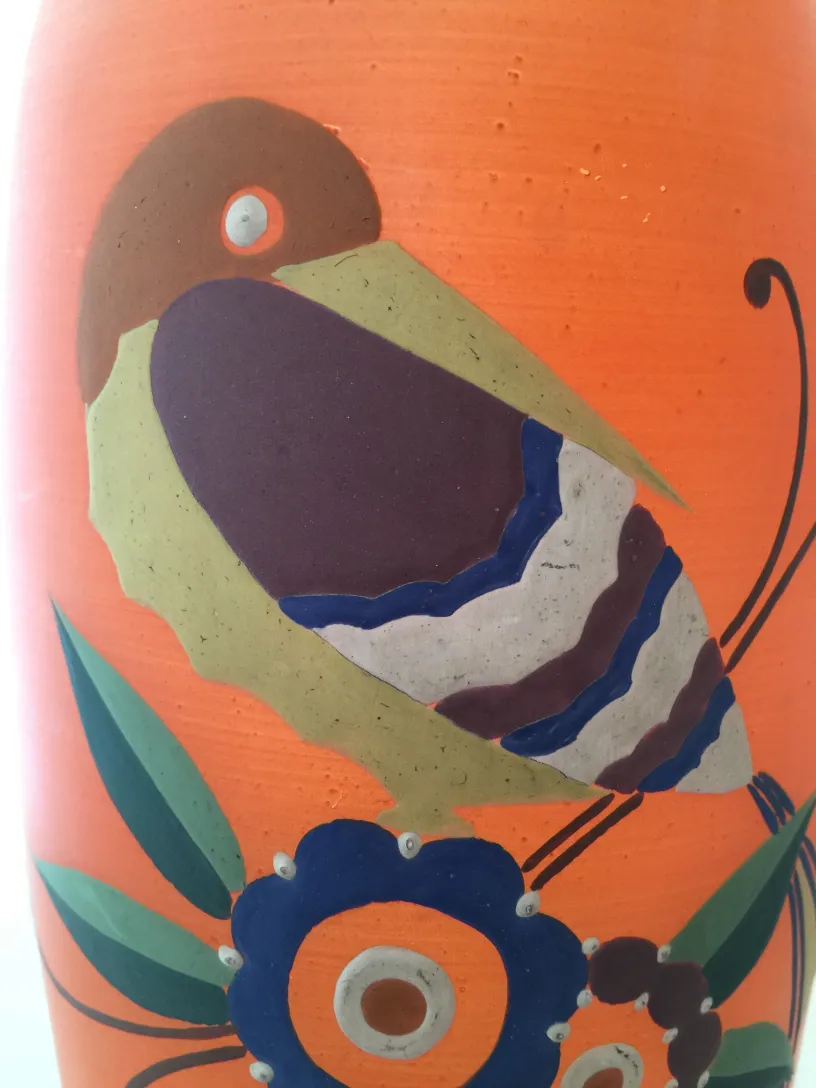 Vase ancien avec un design coloré d'oiseaux et de fleurs, fond lisse.